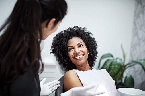 Dentist discussing with smiling female patient