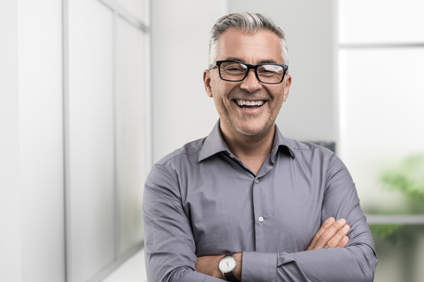 Man smiling with his arms crossed after his ridge augmentation procedure at Djawdan Center for Implant and Restorative Dentistry.